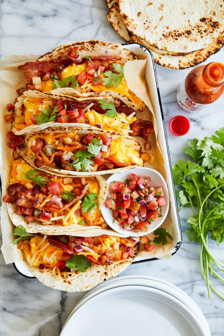 Breakfast Tacos - An absolute crowd favorite! Served in warm tortillas with crispy bacon, potatoes, scrambled eggs and your favorite toppings!