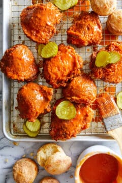 Crisp-fried chicken basted with a cayenne-pepper buttermilk mixture, ready to be served with biscuits and dill pickle.